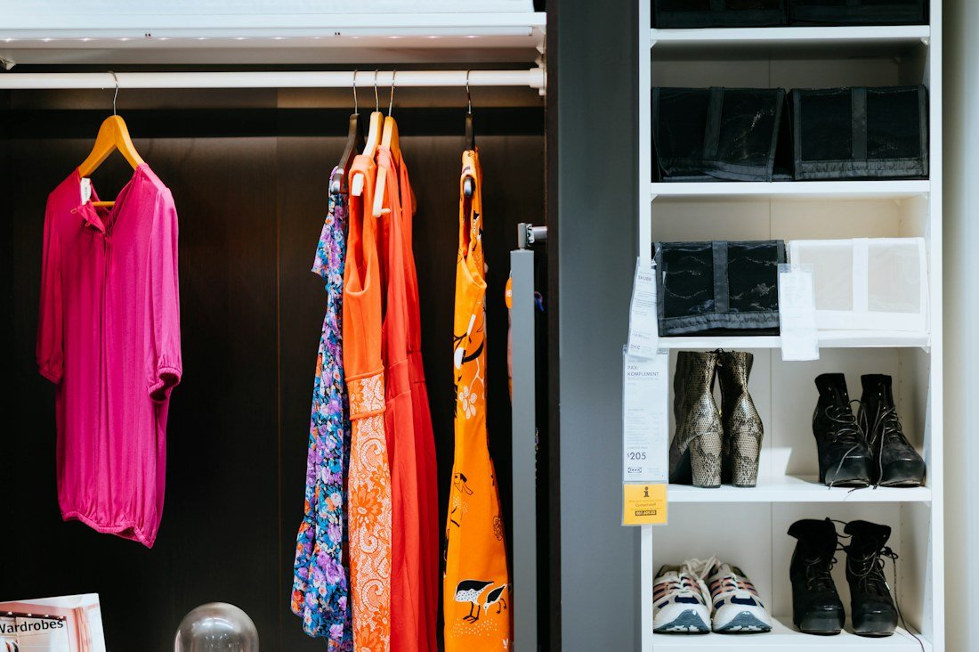 An open wardrobe with brightly colored dresses and shelves of shoes