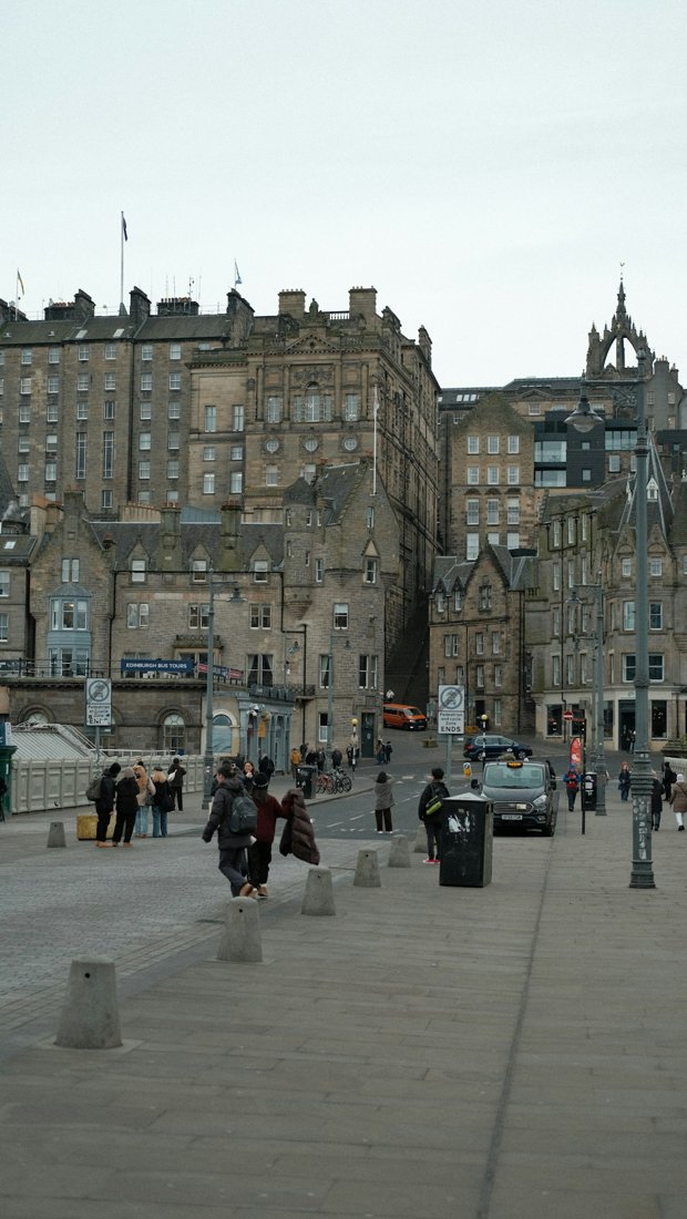 Pedestrians crossing an Edinburgh square surrounded by historic stone buildings